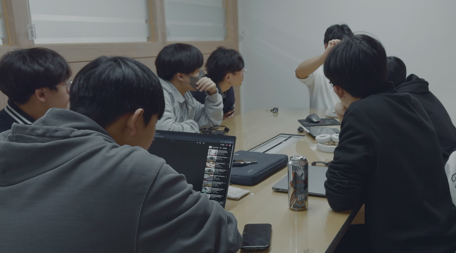 회의실 테이블에 둘러앉아 노트북을 함께 보며 논의하는 팀원들.